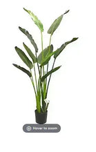 Potted artificial travelers palm plant with green fronds in a dark pot