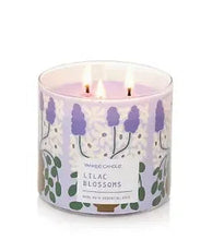 Scented 3-wick candle in white jar with lilac blossoms and lit wicks