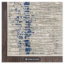 Area rug corner with cream base and blue abstract pattern, textured weave