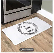 Rectangular anti-fatigue kitchen mat with white surface and black “Home sweet home” wreath