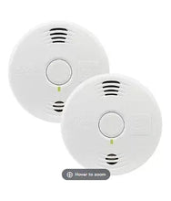 White smoke alarm pair, close view of circular test button and sound vents