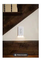 Installed wall outlet night light with white wall plate and built-in LED glow.