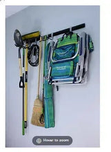 Wall-mounted utility storage rail with black metal hooks and hangers