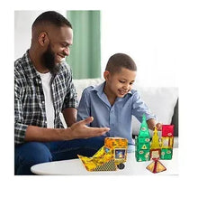 Magnetic tile construction set with colorful pieces and trucks on a table, kid playing