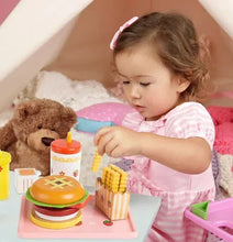 Toddler playing with cheeseburger toy set, including burger, fries, drink cup, and tray