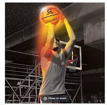 Light-up LED basketball held near a hoop, orange glow over the ball