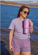Purple insulated stainless steel tumbler with lid and straw, held by person
