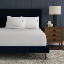 Two white down-alternative pillows with embroidered logo