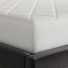 White fitted mattress pad at bed corner with stitched edge