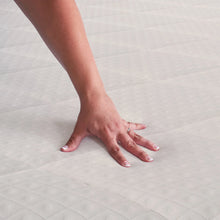 White quilted mattress pad with hand smoothing the surface