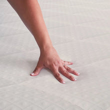 White mattress pad with quilted texture as hands smooth the top