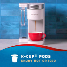 K-Cup coffee pods brewing in a machine with a red mug on a counter