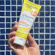 SPF 50 sunscreen lotion tube in hand, yellow label and white squeeze cap.