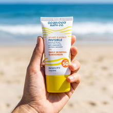 Hand holding invisible mineral sunscreen SPF 50 tube with yellow base