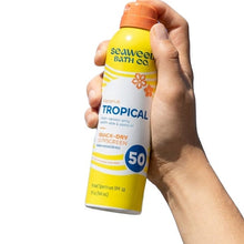 Tropical SPF 50 quick-dry sunscreen spray bottle held in hand, orange cap