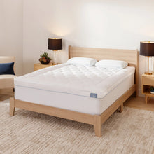 White quilted mattress topper on bed with two pillows, rectangular fit