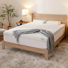 Cooling memory foam mattress topper on wooden bed base, quilted white top
