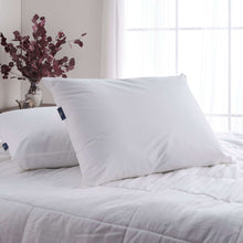 White cooling pillow on a bed with quilted white bedding