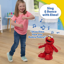 Red Elmo plush next to a child, with big white eyes and orange nose