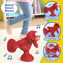 Red Elmo plush on the floor with posed arms, orange nose and white eyes