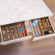 Acacia drawer organizer set with open compartments holding blue utensils and cutlery