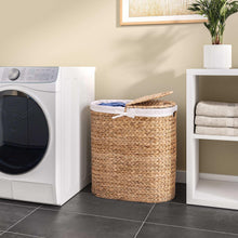 Handwoven water hyacinth laundry hamper with white fabric liner and bow-tied lid
