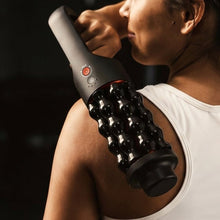 Handheld rolling massager with dark handle and row of glossy rollers