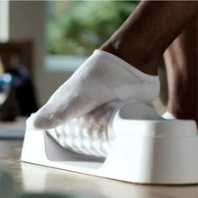 Rolling massager under a socked foot; ribbed rollers and base visible