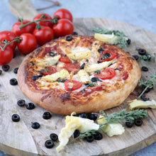 Round pizza on perforated mat with tomato, basil, olives, and melted cheese