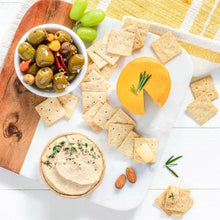 Almond flour sea salt crackers with olives and cheese dip on a wooden board