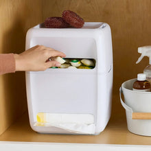 White trash bag & dish pod organizer with hand placing pods in the top tray