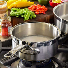 Stainless steel saucepan on stovetop with loop handles, interior visible