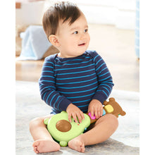 Green rock-a-mole guitar baby toy in baby’s hands with colorful light buttons
