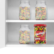 Skittles 54 oz candy jar on a shelf, next to clear jars filled with small candies.
