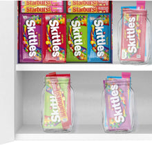 Open candy box with Starburst and Skittles wrappers and two resealable jars