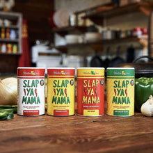 Set of Cajun seasoning cans on a wooden surface with peppers and onions