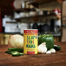 Cajun seasoning can with garlic, onions, and green pepper on a wooden board