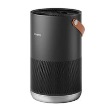 Air purifier with dark cylindrical body, top fan grille, and brown leather carrying strap