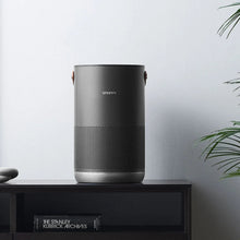 Air purifier with cylindrical body, front speaker-style grille, and bottom silver base