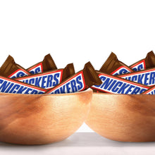 Chocolate candy bars with caramel and peanuts, Snickers wrappers partially shown