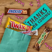 Assorted chocolate candy bars, including Twix and Milky Way, on a wooden surface