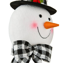 Snowman tree topper close-up with orange nose, smiling mouth, black top hat brim