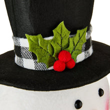 Snowman tree topper hatband with green holly leaves and red berries over plaid