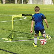 Boy standing beside a neon yellow pop-up soccer goal with white net on grass