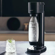 Black sparkling water maker dispensing sparkling water into a glass