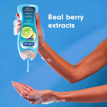 Body wash bottle dispensing over hands, labeled real berry extracts