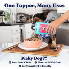 Dog with food bowl while holding a Solid Gold bone broth dog food topper pouch