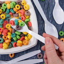 Hand holding white plastic spoon over plate of colorful cereal