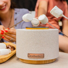 Solo Stove fire bowl on wood base with marshmallows on skewers above the flame