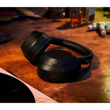 Black over-ear wireless headphones resting on a surface, showing the ULT detail